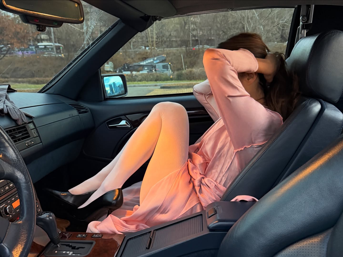 woman tying her hair in car