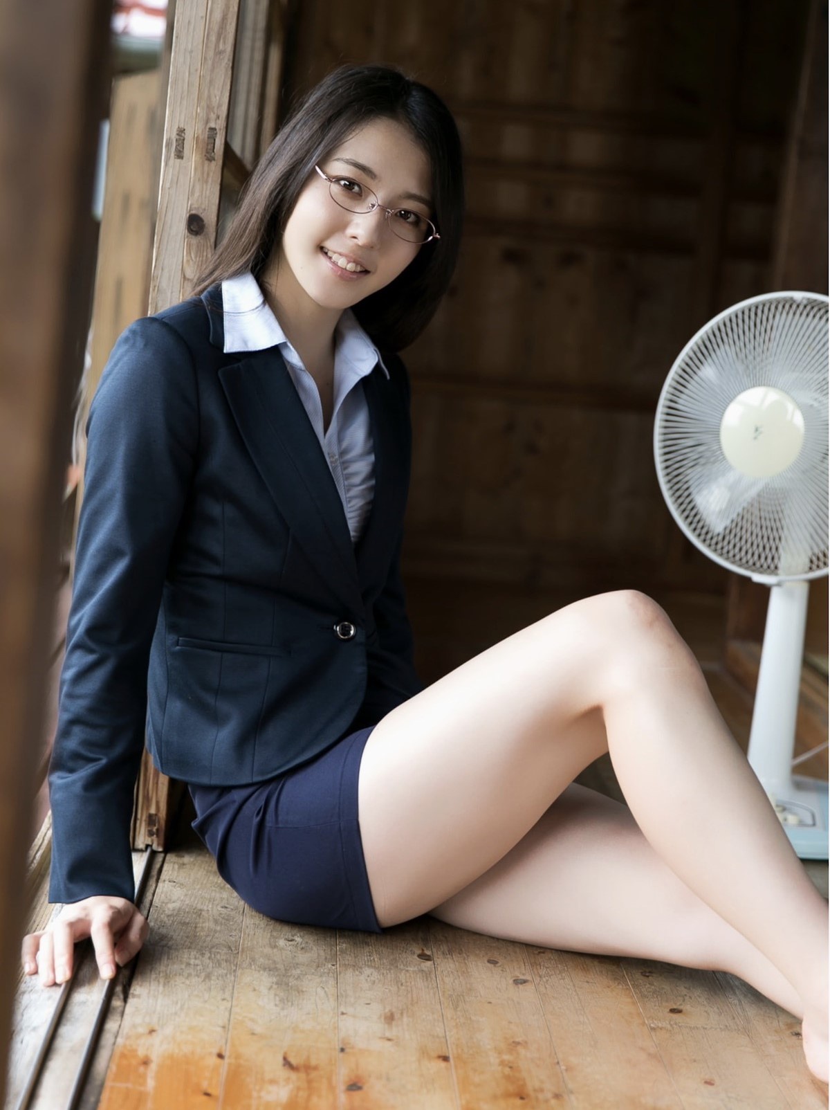 woman with glasses wearing tight skirt sitting on floor indoors
