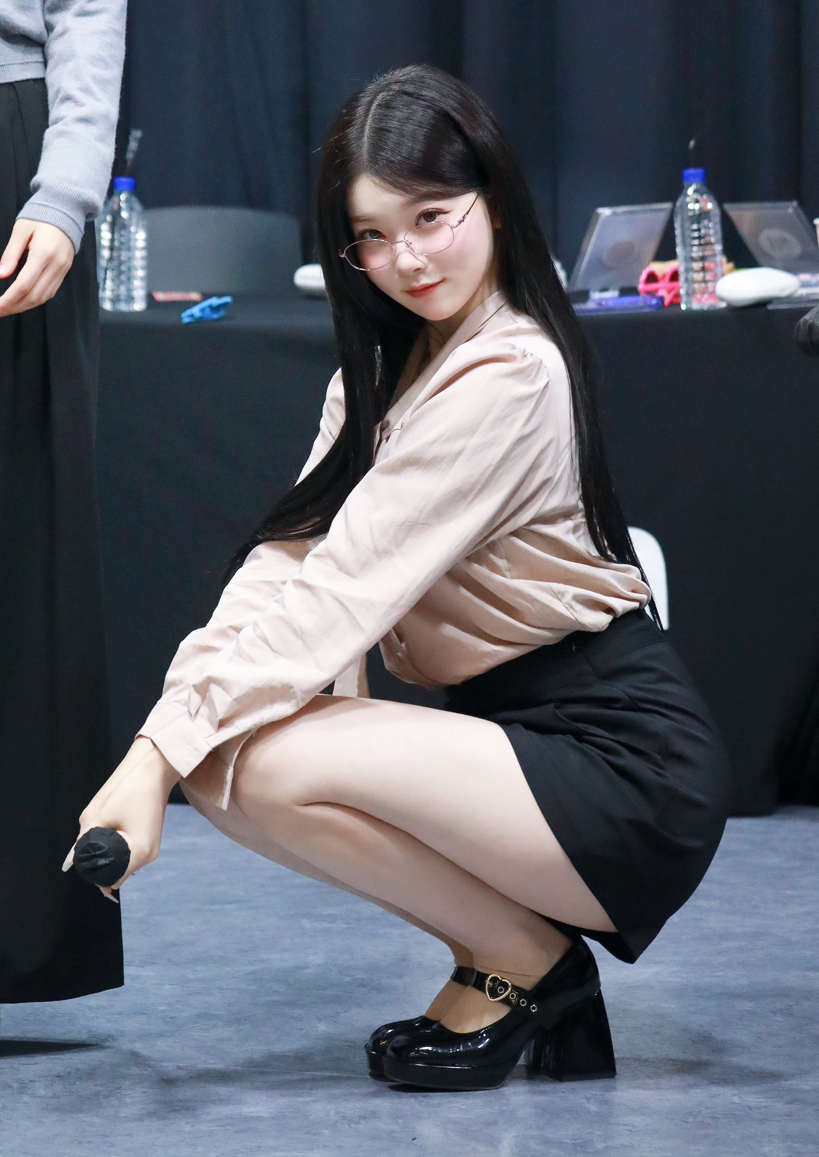 woman wearing glasses squatting with microphone