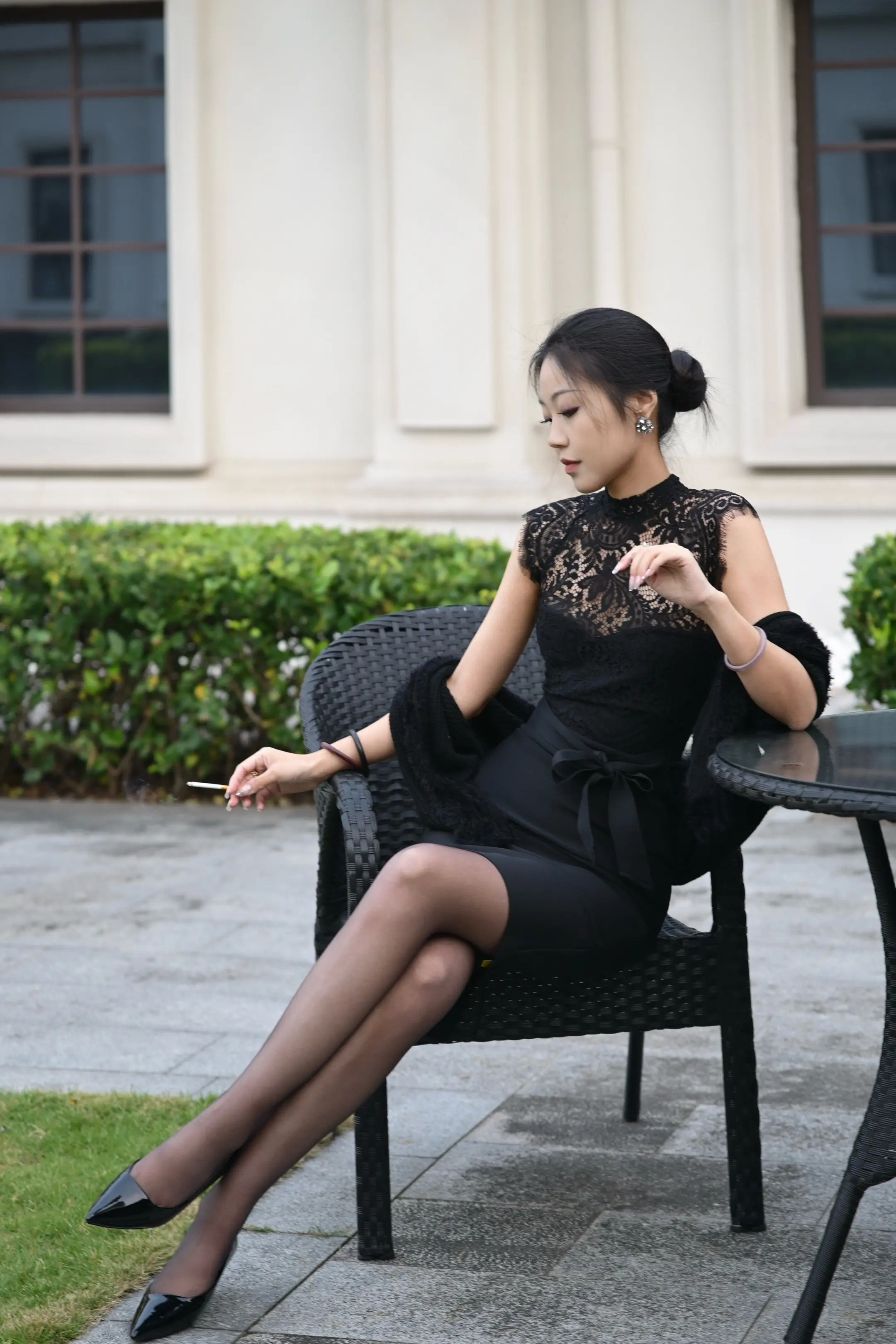 elegant woman wearing black stockings sitting on chair outdoors
